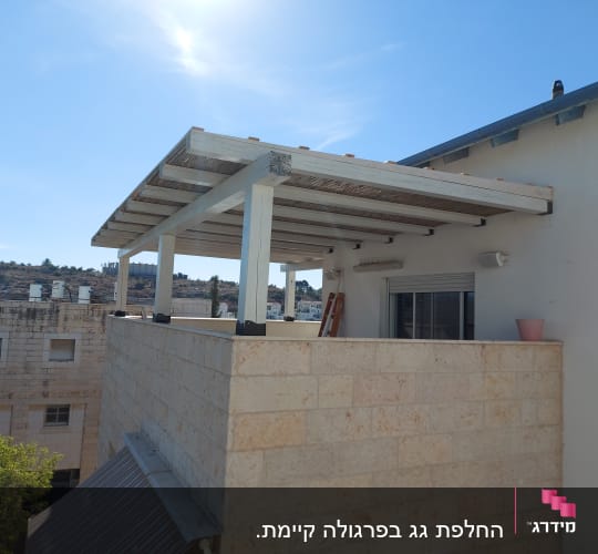 פרגולה מעץ על מרפסת אבן עם עציץ